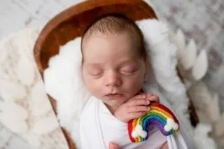 Baby holding a rainbow in a basket