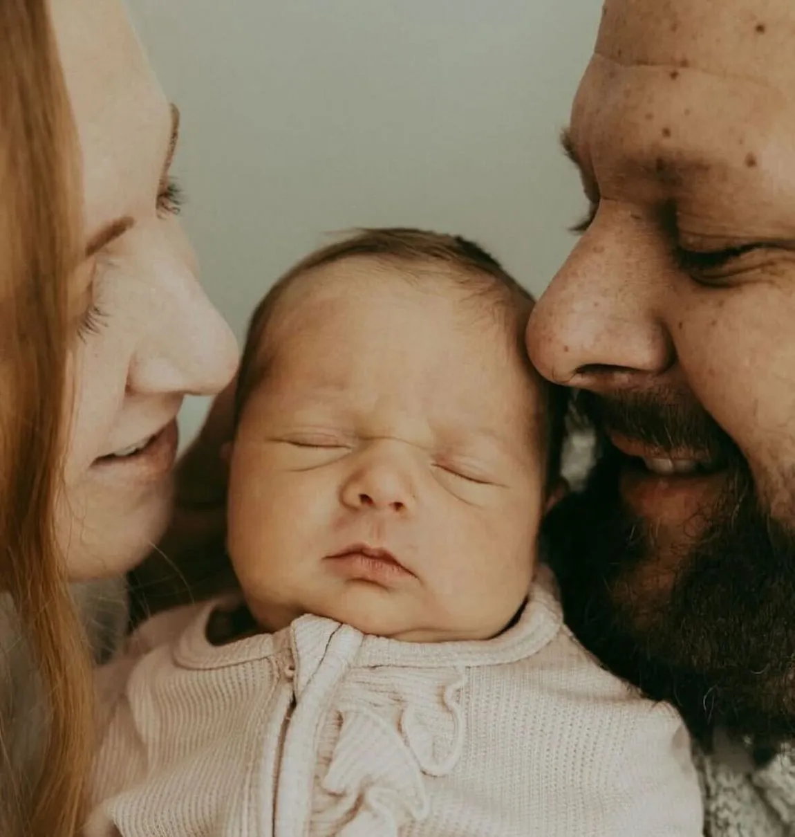 Smiling-parents-snuggling-baby