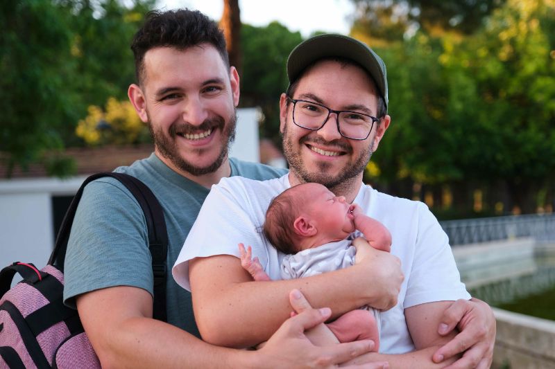 Two happy men with their newborn baby